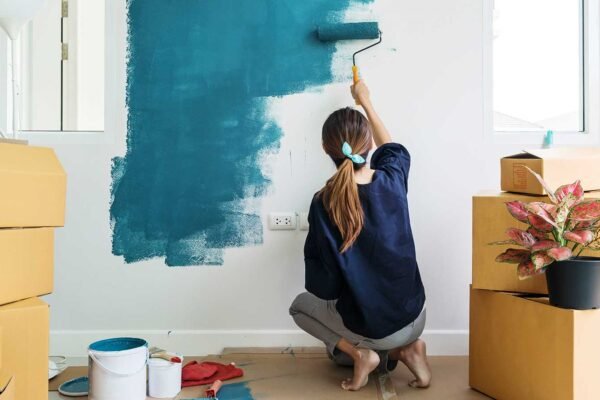 a lady painting her home with blue showing her home improvement