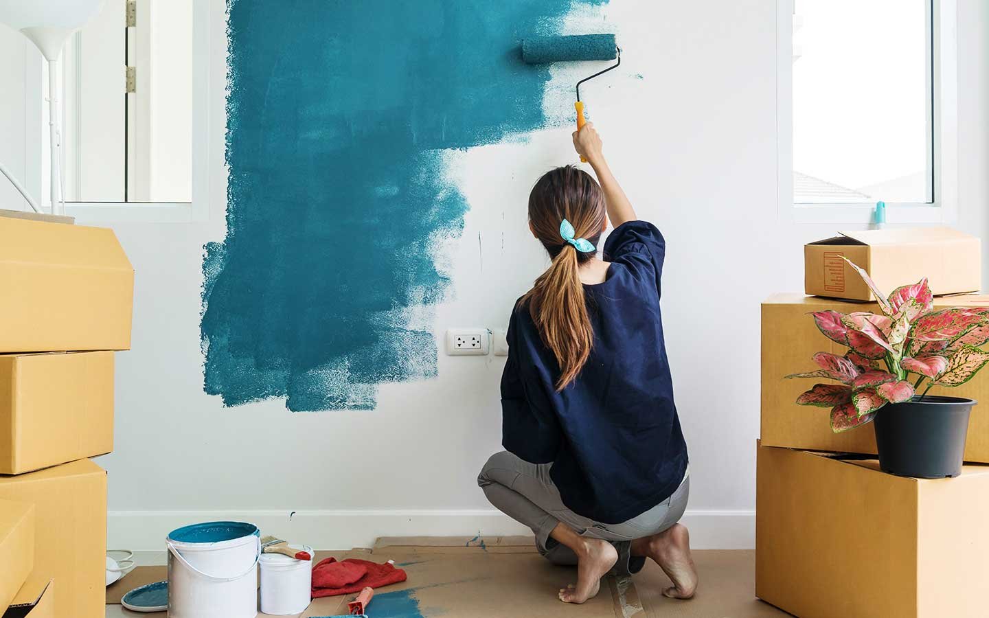 a lady painting her home with blue showing her home improvement